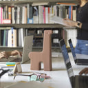 Scultura decorativa Paca in un ufficio moderno, circondata da laptop e libri, aggiungendo un tocco di colore e design.